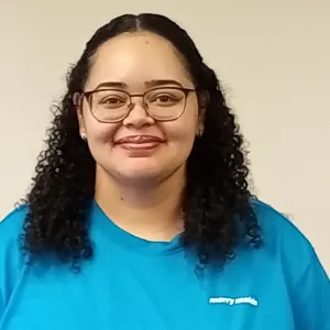 smiling woman with a blue merry maids uniform standing in front of a tan wall